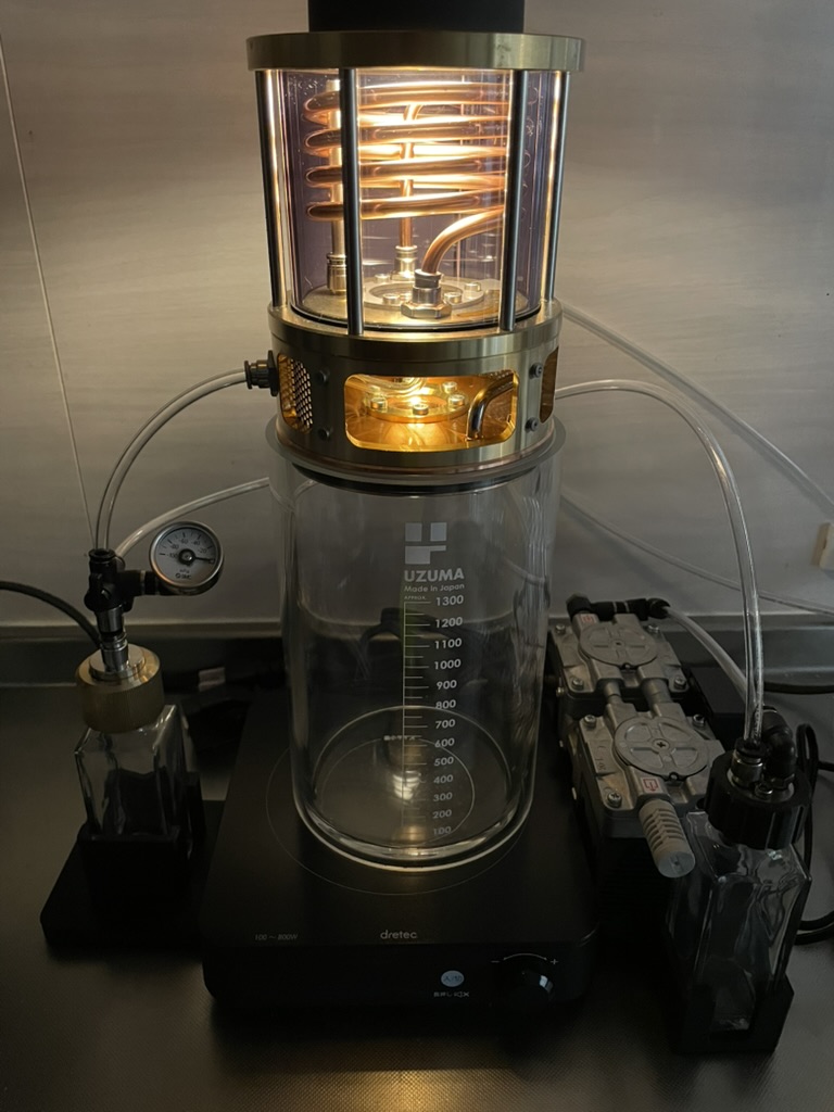 家庭での減圧蒸留シーン（テーブルに置かれた装置とグラス）